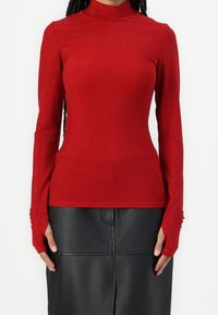 Rotes Langarmoberteil mit hohem Kragen, aus einem glitzernden Material gefertigt. Verfügt über ein figurbetontes Design und Daumenschlitze an den Ärmelends.