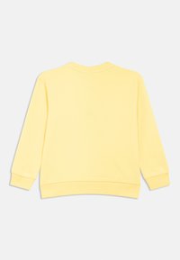 Keltainen collegepaita, jossa on pyöreä pääntie, pitkät hihat ja resorireunukset. Sileä kangas yksivärisenä, ilman näkyviä kuvioita tai koristeita.