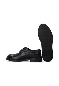 Schwarze Leder-Oxfordschuhe mit durchbrochenen Details, runder Zehenpartie, flacher Sohle und kontrastierender roter Naht am Rand der Sohle.