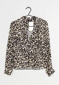Leopardenmuster-Bluse mit langen Ärmeln, V-Ausschnitt, weichem Stoff, hellbeigem Hintergrund und schwarzen Flecken. Hat knöpfbare Manschetten und einen Aufhänger.