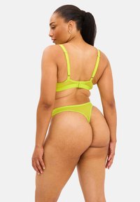 Limegrøn lingeriset bestående af en gennemsigtig bh og en matchende trusse, med justerbare stropper og en tekstureret overflade.