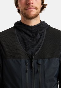 Czarna odzież wierzchnia zapinana na zamek z teksturowanym, puszystym kapturem z polaru i siateczkową górną częścią. Posiada podwójne zamki błyskawiczne oraz gładkie panele materiałowe poniżej.