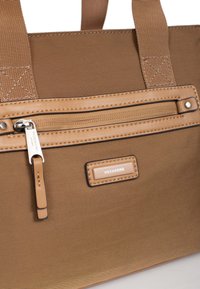 Borsa a mano in tessuto marrone con tasca frontale con zip, dettagli in pelle beige e una placca rettangolare con logo. Presenta una struttura resistente in tessuto e manici in nylon.