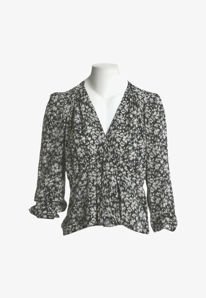 Blouse à imprimé floral noir et blanc avec manches trois-quarts bouffantes et col en V sur un buste de mannequin blanc.