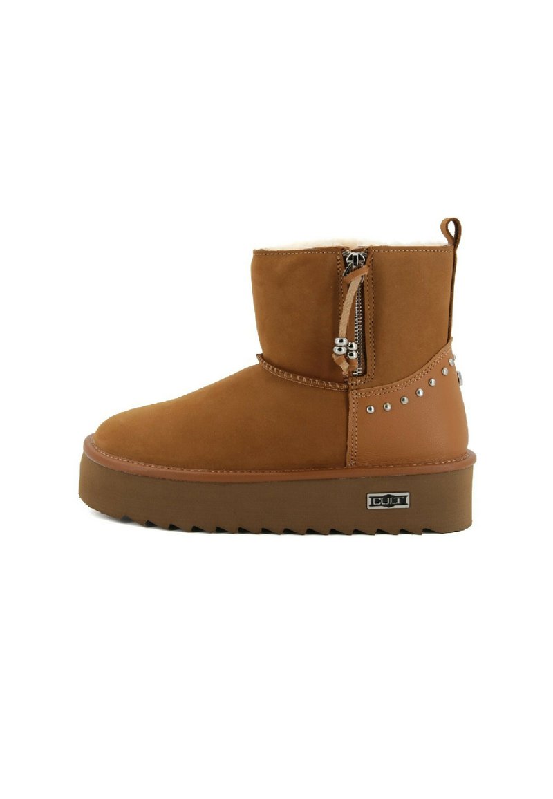 Brązowy zamszowy zimowy but z bocznym zamkiem błyskawicznym, metalowymi ćwiekami na pięcie, grubą gumową podeszwą z rowkami i logo marki na krawędzi podeszwy.