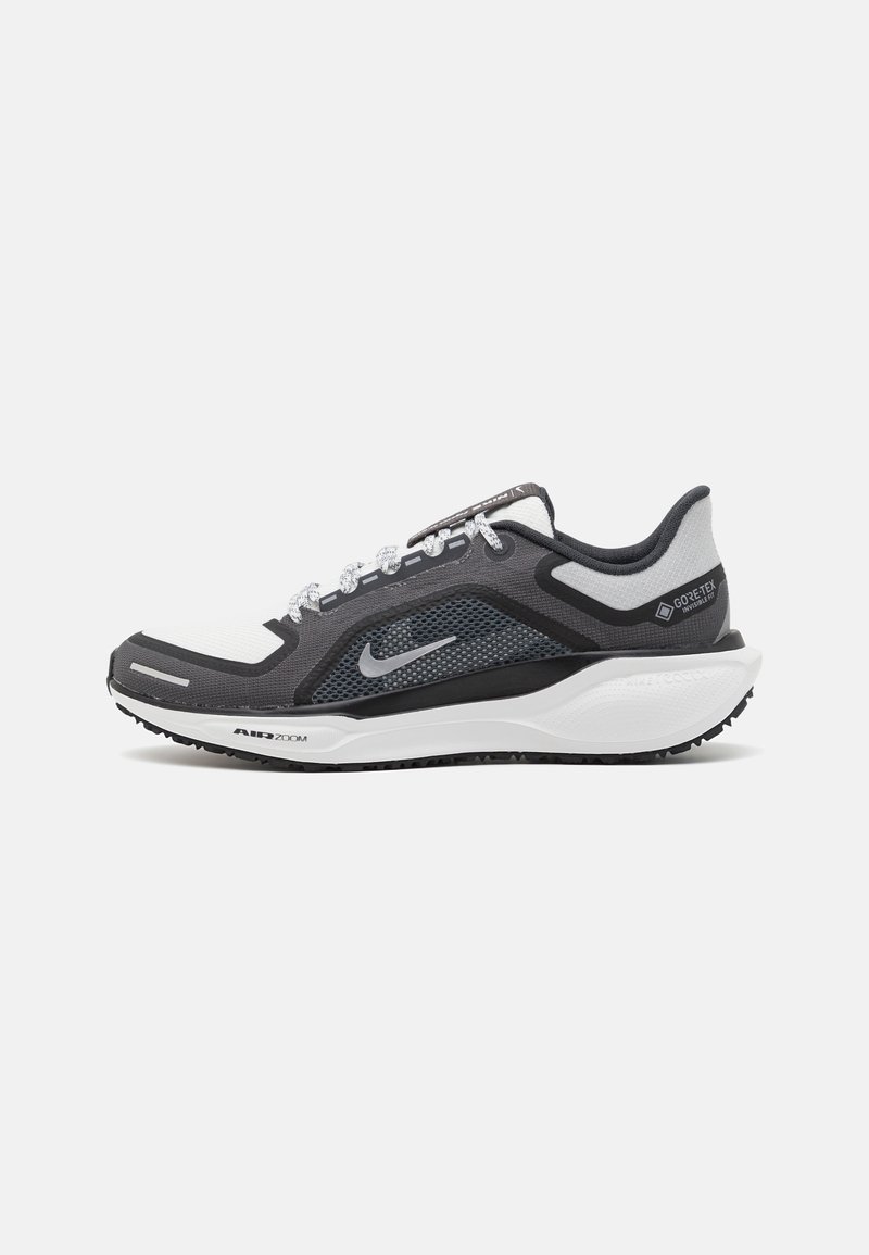Schwarzer und grauer Sportschuh mit einem Mesh-Obermaterial, reflektierenden Akzenten und einer weißen Zwischensohle. Verfügt über eine strukturierte Gummisohle und Schnürsenkel.