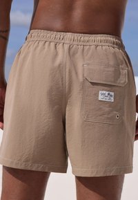 Beezhi ujumispüksid kummiga vöökohal, küljetasku ja brändi sildiga. Tekstureeritud kangas veekindla viimistlusega.