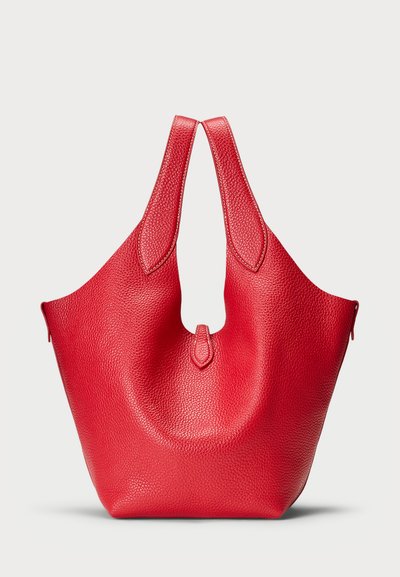 Sarkans ādas soma ar teksturētu virsmu, kurai ir unikāla forma un divas rokturīgas. Dizains ietver apaļu izgriezumu centrā.