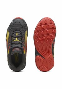 Scarpa da ginnastica grigia e gialla con tomaia in mesh, collo imbottito, suola esterna rossa con trazione in gomma e logo prominente sul lato.