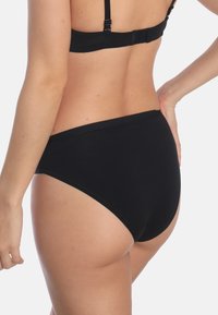 Zwarte hoge taille onderbroek van gladde stof, met een naadloos ontwerp en een zachte tailleband. De achterzijde biedt bescheiden bedekking.