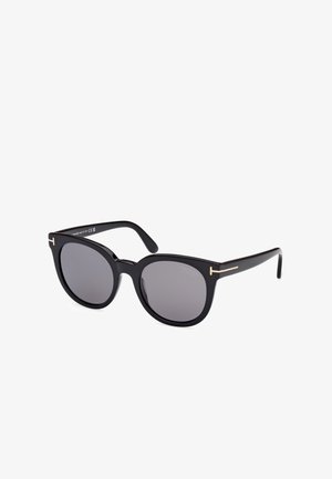 Ochelari de soare supradimensionați, de culoare neagră, cu lentile închise, cadru din plastic și accente din metal auriu pe temple. Formă clasică de cat-eye.