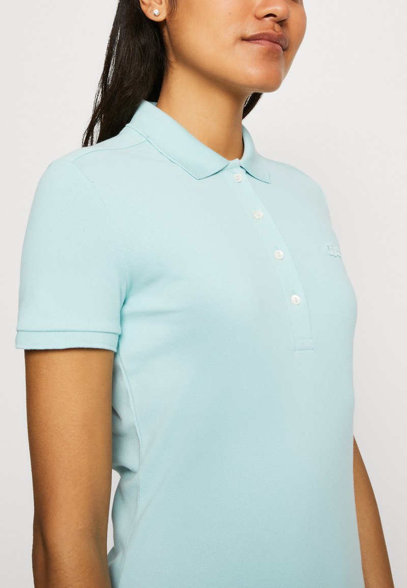 Polo shirt azzurro chiaro con colletto classico, maniche corte e patta con tre bottoni. Caratterizzato da un tessuto testurizzato e logo sul petto.