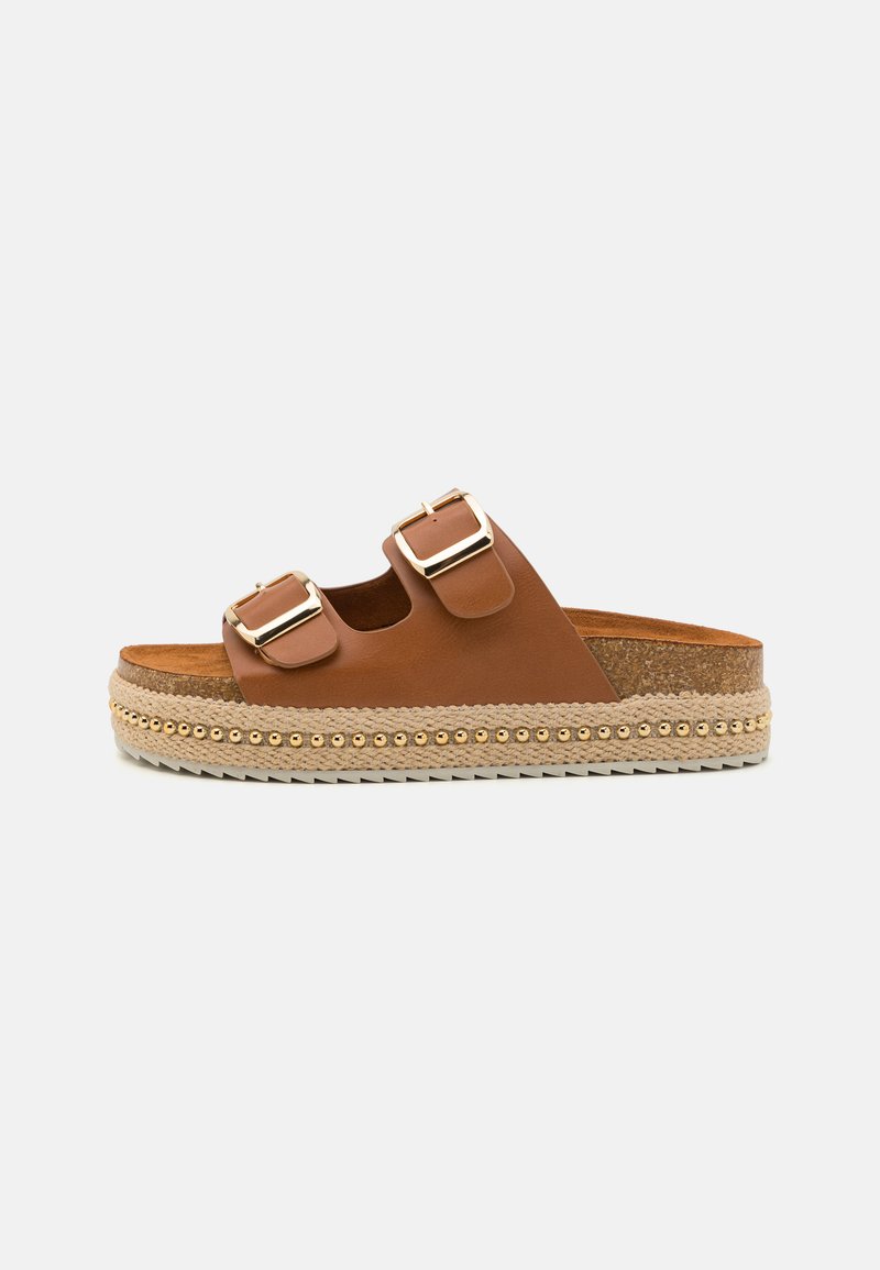 Chanclas de cuero marrón con dos correas ajustables y hebillas doradas. Suela tipo plataforma con textura trenzada y pequeños acentos dorados.