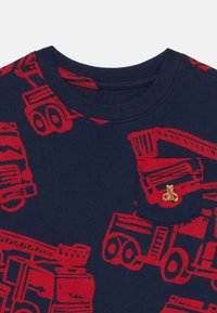 Marineblauses T-Shirt mit roten Lastwagenmustern, ausgestattet mit einer kleinen Tasche, die mit einer Teddy-Bären-Stickerei verziert ist. Aus Baumwollmaterial, im Crew-Neck-Design.