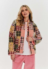 Prošívaná bunda s patchworkovým designem, který kombinuje kostkované a květinové vzory v živých barvách, doplněná růžovou podšívkou a zipem.