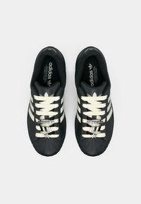 Μαύρα αθλητικά παπούτσια με ανάγλυφη λαστιχένια μύτη, τρεις λευκές ρίγες και κρεμ κορδόνια. Διαθέτει ασημένιο λογότυπο και αστέρι ως διακοσμητικό στα κορδόνια.