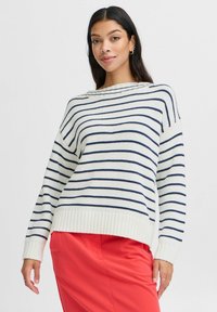 Gestreifter Strickpullover in Cream mit dunkelblauen Streifen, verf�ügt über einen gerippten Saum und einen lockeren Schnitt. Getragen über einem roten Rock.