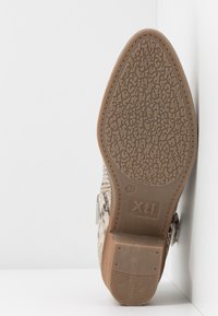 Semelle d'une bottine femme à bout pointu avec motif texturé, taille 37, de la marque Xti, avec un petit talon empilé et une tige à imprimé serpent.
