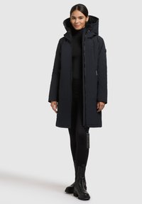 Padded black parka bunda s vysokým golierom, predným zipsom, bočnými vreckami a visačkou. Disponuje hladkým povrchom a voľným strihom.