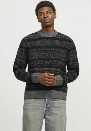 Stickad tröja med svarta och grå horisontella ränder, ribbad krage och manschetter, texturerat mönster och avslappnad passform. Bärs med ljusblå jeans.