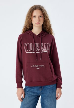 Sweat-shirt à capuche bordeaux avec une poche avant, mettant en avant "COLORADO" en lettres blanches et un texte décoratif sur la poche en blanc contrastant.