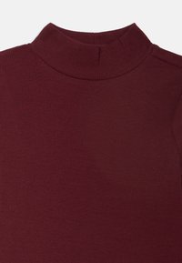 Burgunderfarbener, gerippter Rollkragenpullover mit einer figurbetonten Silhouette, ausgestattet mit einem hohen Kragen und einem strukturierten Stoff für zusätzliche Wärme.