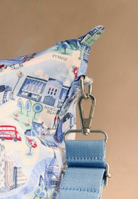 Koti nurk sinise kangast rihma ja hõbedase luku ning Londoni maamärkide, nagu Buckinghami palee ja Püha Pauluse katedraali illustratsioonidega.