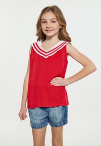 Rød ærmeløs skjorte med en hvid V-halskrave, der har tre røde striber. Bæres med denimshorts. Glat stof, afslappet design.