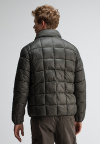 Dunkelgrüne Daunenjacke mit hohem Kragen, mit gestepptem Muster und genähten Details. Entworfen für Wärme mit einer taillierten Silhouette.