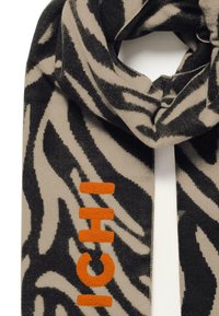 Sciarpa a maglia con motivo a zebra in nero e beige, caratterizzata da un logo "ICHI" arancione audace. Tessuto morbido e design rilassato.
