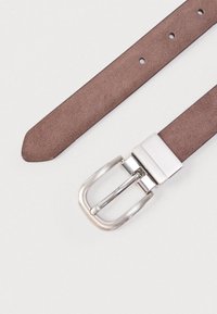 Καφέ σουέτ ζώνη με λαμπερή ασημένια μεταλλική αγκράφα. Διαθέτει κωνικό άκρο και πολλαπλές οπές ρύθμισης στο λουρί. Ομαλή υφή συνολικά.