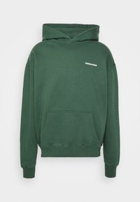 Grön hoodie i bomull med en känguruficka. Har en vit logotyp "PEGADOR" på bröstet. Mjuk textur, ribbade muddar och nederkant.