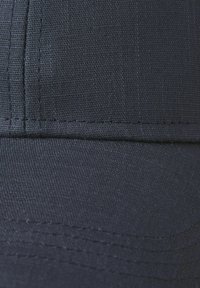 Casquette de baseball bleu marine en tissu texturé, avec des coutures bien marquées le long de la visière et des panneaux latéraux.