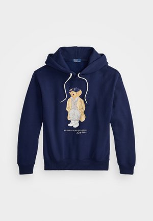 Tummansininen huppari, jossa valkoiset nauhat, edessä tyylikkäästi pukeutuneen karhun brodeeraus. Puuvillasekoitekangas.