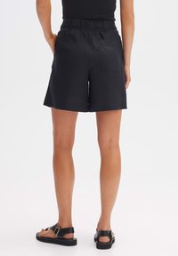 Shorts noirs en tissu léger, dotés d'une taille élastique, d'une poche au dos et d'une coupe décontractée avec une longueur mi-cuisse.