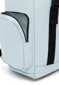 Hellblauer Rucksack aus glattem synthetischem Material. Verfügt über eine schwarze Reißverschlusstasche an der Seite, mit flachen Riemen und Nahtakzenten.