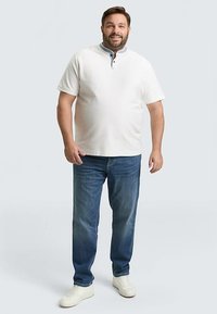 Lichtgekleurde korte mouwen polo met een geknoopte kraag, gecombineerd met een blauwe spijkerbroek en witte sneakers. Casual pasvorm met een gladde textuur.