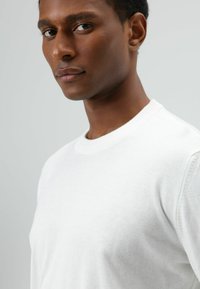 Witte gebreide trui met een ronde hals, met een gladde textuur. De stof lijkt licht en zacht, geschikt voor casual dragen.