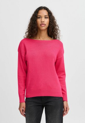 Pull en tricot fuchsia avec un large col bateau, des manches longues, un ourlet côtelé et une coupe légèrement ample. Porté sur un jean foncé.