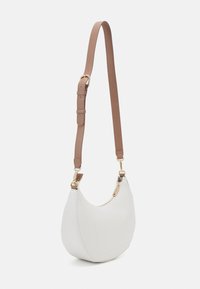 Vit läderaxelväska med en böjd design, med en brun justerbar rem och detaljer i guldfärg. Dragkedjestängning i toppen, minimal sömnad.