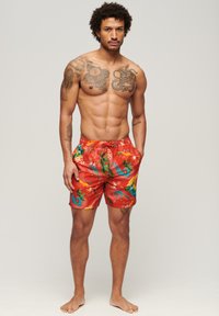Pantaloni da bagno rossi con una vivace stampa tropicale di cavallucci marini e fiori. Realizzati in tessuto morbido, con cintura elastica e tasche laterali.