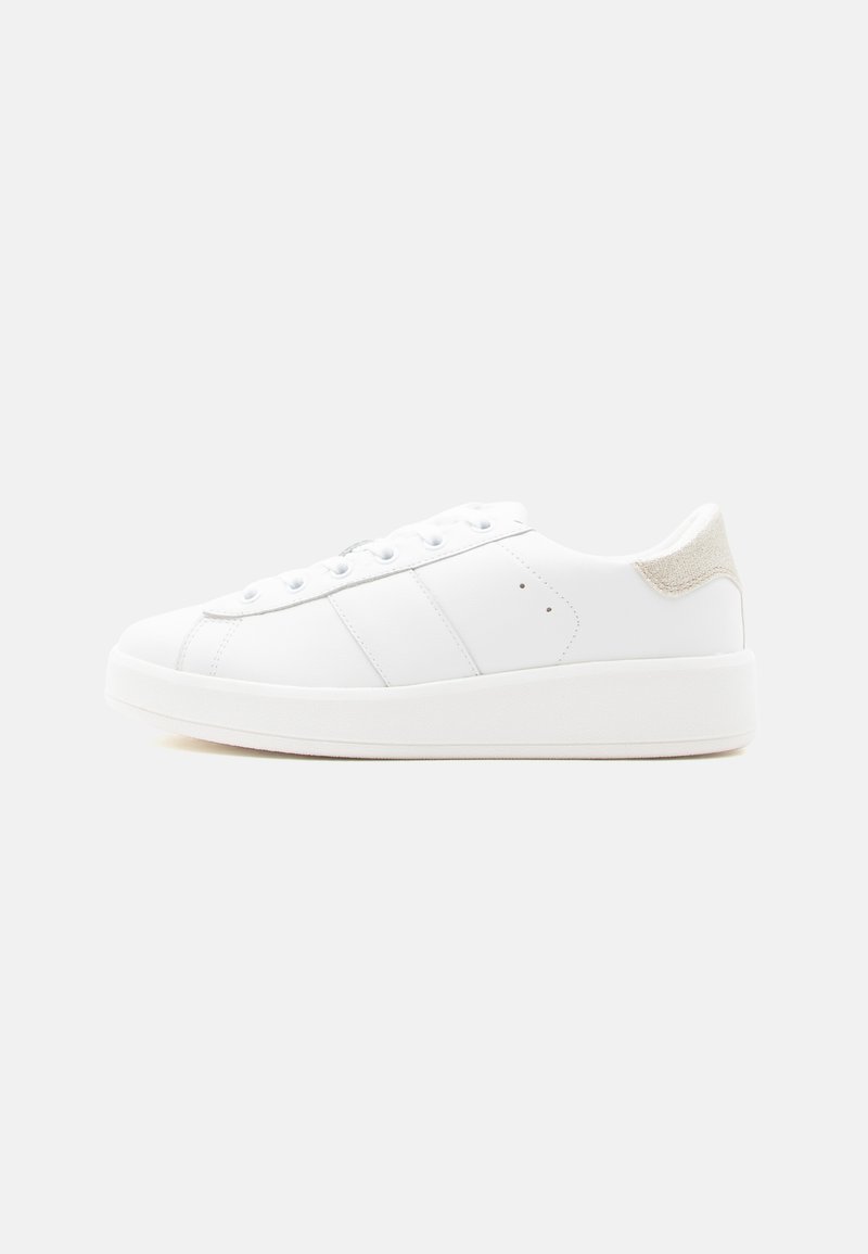 Baskets basses blanches avec laçage à l'avant, tige en cuir lisse, languette de talon beige texturée et semelle en caoutchouc épaisse sur un fond uni.