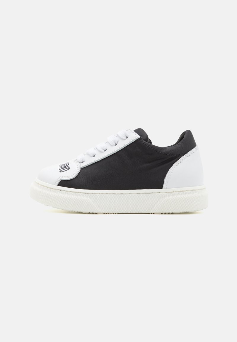 Zapatillas en blanco y negro con un material suave, diseño de corte bajo, puntera redonda, cordones blancos y suela de goma texturizada.