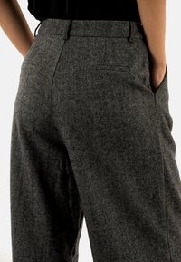 Grijze wollen broek met haringenpatroon, hoge taille, zijzakken en een relaxte pasvorm. Zachte textuur en op maat gemaakte ontwerpelementen.