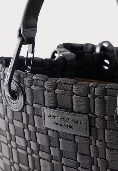 Μαύρη υφαντή τσάντα χειρός με δερμάτινες λαβές και λογότυπο Emporio Armani Milano 1981 στην μπροστινή πλευρά.
