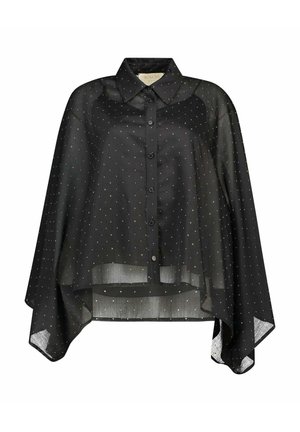 Blusa nera trasparente con bottoni, pois bianchi, colletto appuntito e orlo asimmetrico che scende più lungo ai lati.