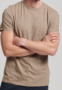 Tričko s krátkým rukávem a kulatým výstřihem v světle hnědé melírované látce; volný střih s viditelnou značkovou nášivkou na levém rukávu.