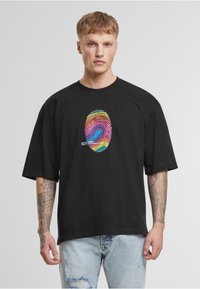Fekete, oversized póló, középen színes ujjlenyomat grafikával, rövid ujjakkal és kerek nyakkivágással.