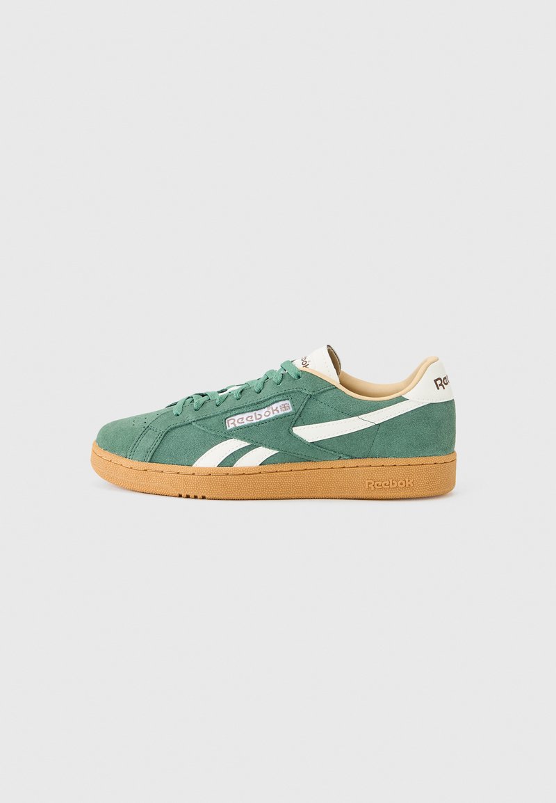 Grønn sneakers i semsket skinn med lavt skaft fra Reebok med hvite logoer og lysebrun gummisåle, vist i profil mot en ensfarget bakgrunn.