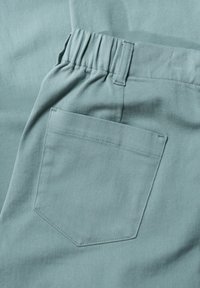 Pantaloni di cotone celeste con tessuto strutturato, dotati di vita elastica e una piccola tasca applicata sul retro.